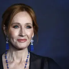 J.K. Rowling z rudymi włosami, niebieskimi oczami i niebieskimi kolczykami.