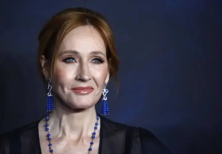 J.K. Rowling z rudymi włosami, niebieskimi oczami i niebieskimi kolczykami.