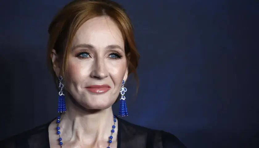 J.K. Rowling z rudymi włosami, niebieskimi oczami i niebieskimi kolczykami.